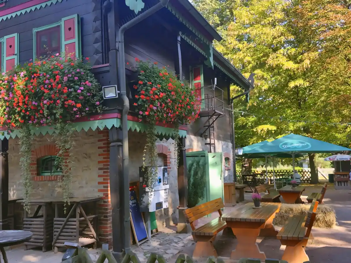 Terrasse am Forsthaus Leiner Berg mit Holzbänken, Sonnenschirmen und Blumenkästen